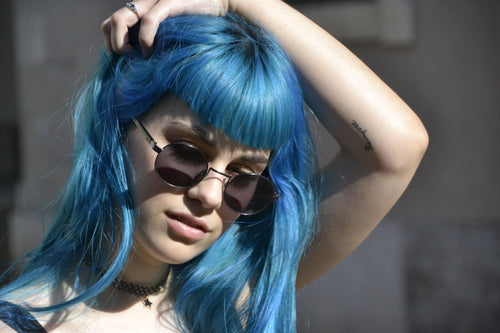 Woman wearing sunglasses with vibrant blue hair dyed by Manic Panic