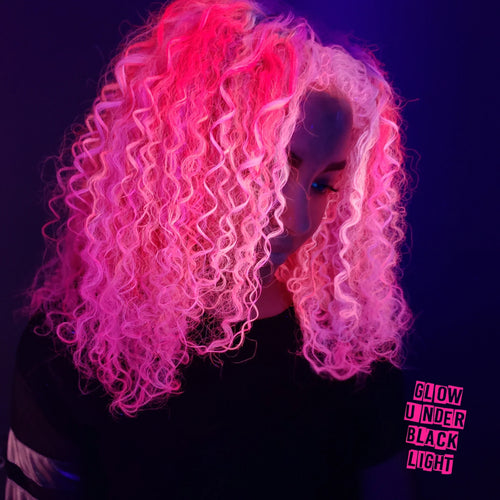 Model with curly hair colored neon pink using Manic Panic UV reactive hair dye that glows under blacklight
