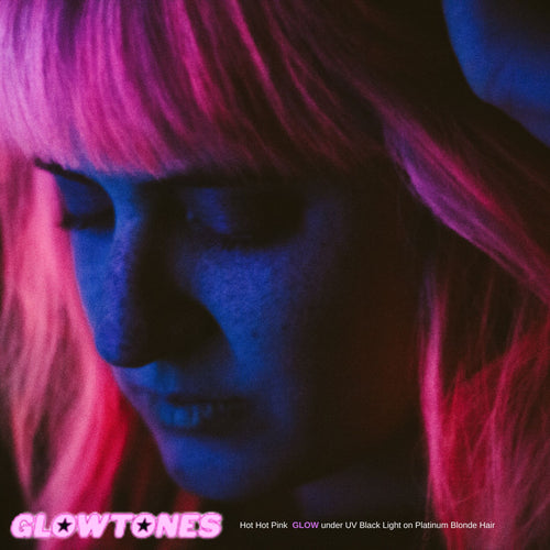 Close-up of model with bangs  perfectly styled hair in Hot Hot Pink Classic hair dye glowing under UV reactive Blacklight, offering a vibrant and trendy pink shade.