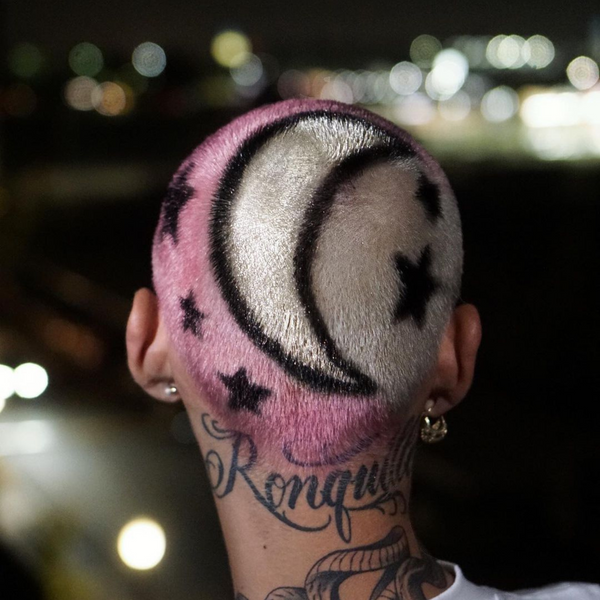 Back of a person's head with pink hair featuring a black half moon and stars design created with silver hair gel  