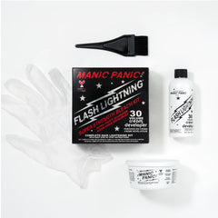 Manic Panic Flash Lighting kit laid out on a white background, including a black applicator brush, a black retail box, a clear protective glove, a white developer bottle, and a white cream container.
