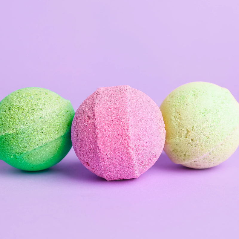 Three colorful bath bombs on a purple background