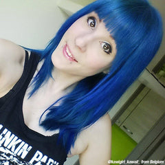 A woman with blue hair and a black tank top, styled with Manic Panic After Midnight dye.